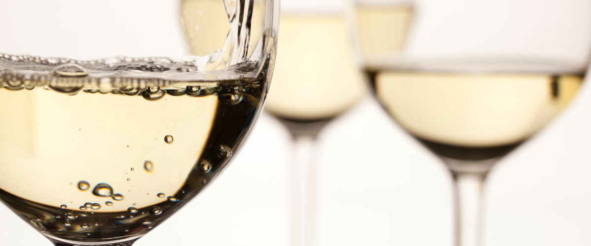 close up of a glass of white wine; two glasses slightly out of focus behind it